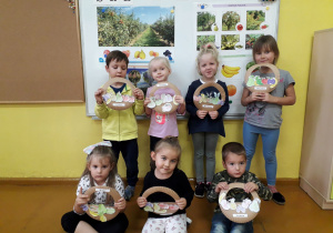 Dzieci prezentyją wykonaną pracę plastyczną owocowy koszyczek.